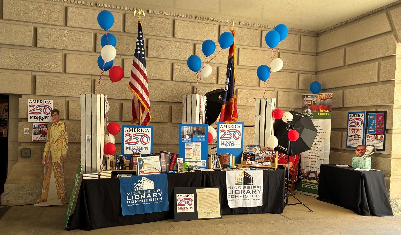 Mississippi Library Commission booth with books, posters, and balloons celebrating America 250.