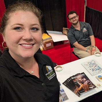 Mississippi Library Commission booth with brochures and magazines on a white table, including a stack titled ‘Mississippi.’