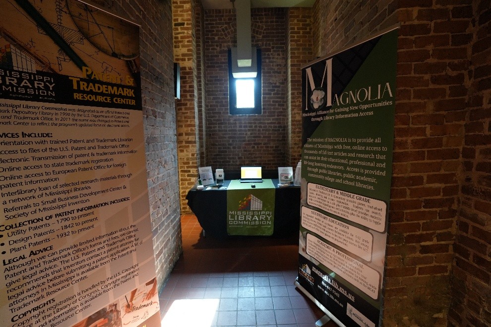 Mississippi Library Commission booth with brochures displayed between two tall banners for Trademark Resource Center and Magnolia.