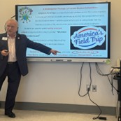 Marvin Jeter points to a screen displaying “America’s Field Trip” and presentation text.